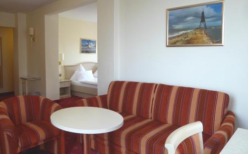 a living room with a couch and a table and a bed at Seehotel Neue Liebe in Cuxhaven