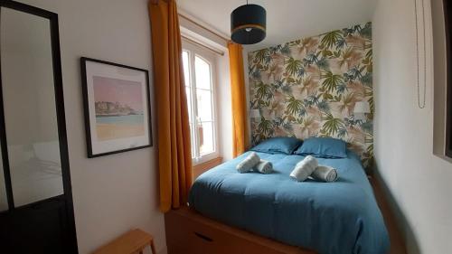 une chambre avec un lit avec des draps bleus et une fenêtre dans l'établissement Beau T2 cosy ! Centre 200m Plage 400m, à Dinard