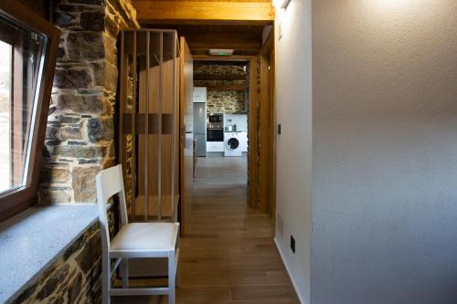 a hallway with a stone wall and a white chair at Refuxio de Lamas in Becerreá