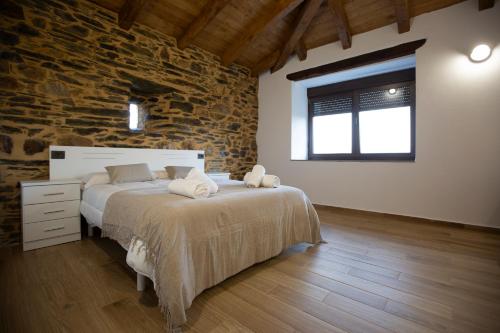 a bedroom with a bed and a stone wall at Refuxio de Lamas in Becerreá