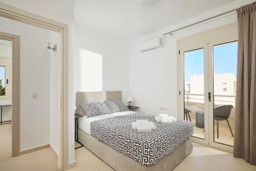 a white bedroom with a bed and a balcony at Angel's Villa in Kato Gouves