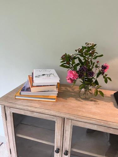 a table with books and a vase of flowers on it at Mizzle Cottage in Cloghjordan