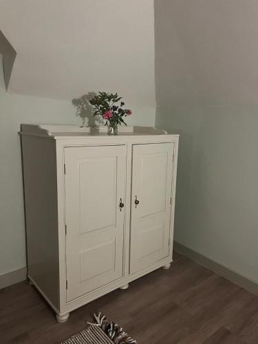 a white cabinet with a vase of flowers on it at Mizzle Cottage in Cloghjordan