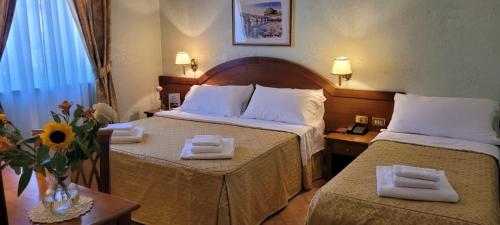 una camera d'albergo con due letti con asciugamani sopra di Hotel Squarciarelli a Grottaferrata