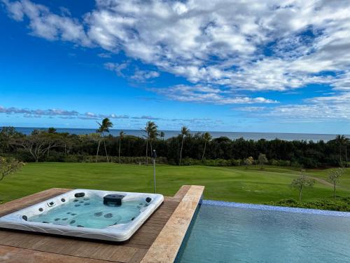 a hot tub on a deck next to a golf course at Private Luxury 6-bedroom Villa in Kukuiula, Panoramic Ocean View, Heated infinity pool, SPA, Sleep up to 22 in Koloa