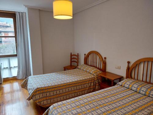 a hotel room with two beds and a window at Céntrico apartamento en el casco antiguo de Potes in Potes