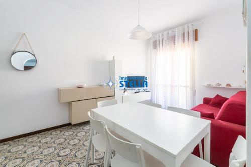 salon z białym stołem i czerwoną kanapą w obiekcie Condominio International w mieście Lido di Jesolo