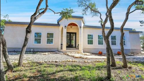 a house with trees in front of it at Cheerful Lakeside Retreat-Just Minutes to the lake in Canyon Lake