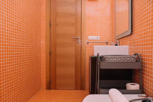 a bathroom with orange tiled walls and a toilet at Cómodo luminoso y céntrico by CABANA Rentals in Vigo