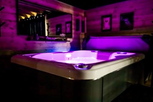 a purple bath tub in a room with a mirror at Le Chalet des Amoureux SPA Sauna in Lozinghem
