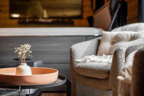 a pot on a table next to a couch and a chair at Le Chalet des Amoureux SPA Sauna in Lozinghem