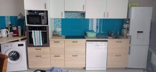 a kitchen with white cabinets and a washer and dryer at L'ampli sur jardin in Noirmoutier-en-l'lle