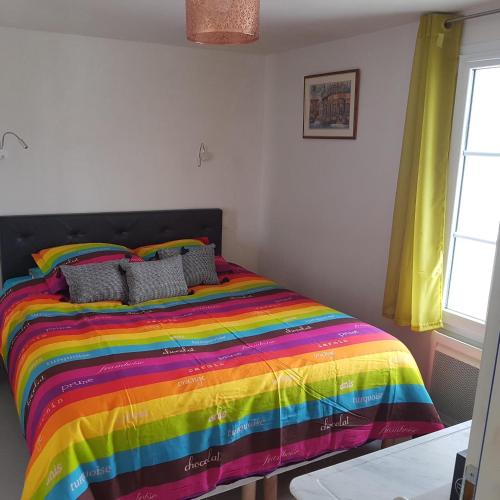 - un lit arc-en-ciel avec des oreillers et une couverture arc-en-ciel dans l'établissement L'ampli sur jardin, à Noirmoutier-en-l'lle