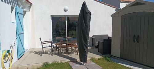 a patio with a table and chairs and an umbrella at L'ampli sur jardin in Noirmoutier-en-l'lle