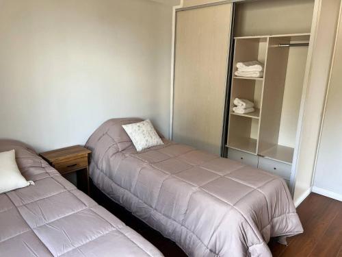 a bedroom with two beds and a shelf with towels at Gray Fox Apartments - Antártida in Ushuaia