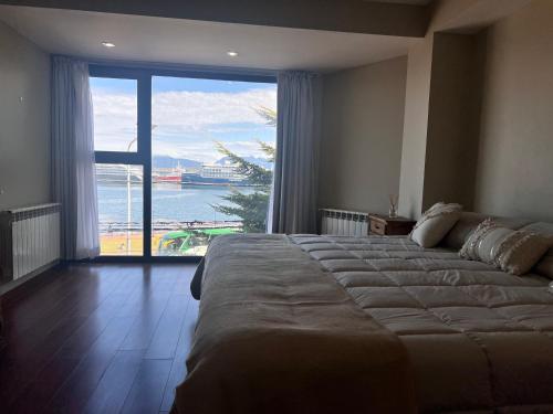 a bedroom with a large bed and a large window at Gray Fox Apartments - Antártida in Ushuaia