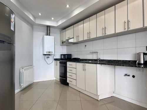 a kitchen with white cabinets and a sink and a stove at Gray Fox Apartments - Antártida in Ushuaia