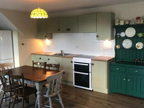 a kitchen with green cabinets and a wooden table at Mournes Family Cottage with Hot Tub in Hilltown
