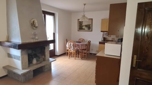 a kitchen with a fireplace and a table with chairs at Bioledro - Casa Lena in Mezzolago