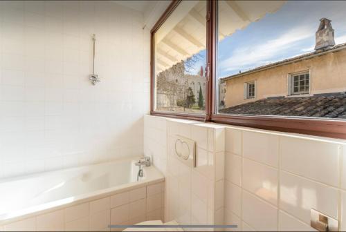 La salle de bains est pourvue d'une fenêtre, d'une baignoire et d'un lavabo. dans l'établissement Au pied du palais clim parking, à Avignon