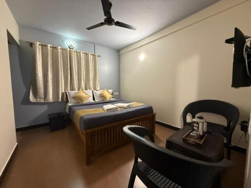 a bedroom with a bed with a fan and a table at Humming Bird suite in Kotagiri
