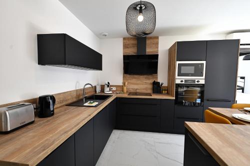 une cuisine avec des armoires noires et des appareils en acier inoxydable dans l'établissement Magnifique T4 neuf à 1km du port de Bonifacio, à Bonifacio