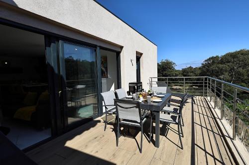 une table et des chaises sur le balcon d'une maison dans l'établissement Magnifique T4 neuf à 1km du port de Bonifacio, à Bonifacio