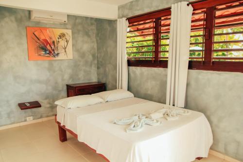 a bedroom with a white bed and a window at Pipa Panorama Aparthotel in Pipa