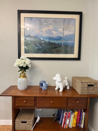 a table with a vase of flowers and a painting at Cosy Retreat at Auburn near Muckleshoot in Auburn