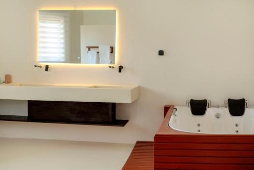 a bathroom with a sink and a tub and a mirror at Tamarin Hôtel Cotonou in Cotonou