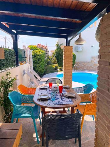 a patio with a table and chairs and a pool at Blue Paradise Seaview villa with private pool in Sounio