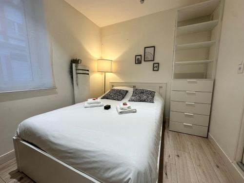 - une chambre avec un grand lit blanc et une commode dans l'établissement Duruy G studio proche piscine et patinoire, à Reims