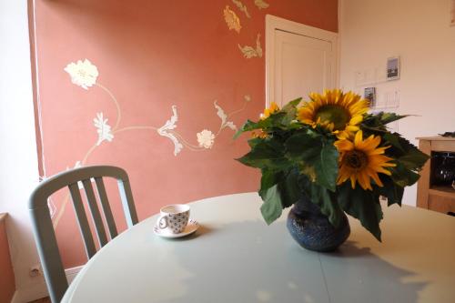 Een vaas met zonnebloemen staat op een tafel, met een kopje ernaast. bij La Maison de 1868 in Vendeuvre