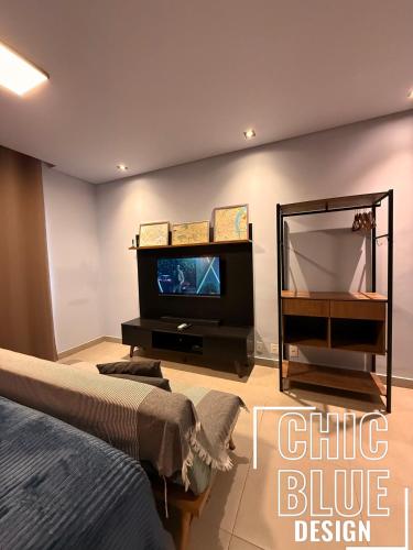 a bedroom with a tv and a bed and a mirror at Chic Blue Design com Vaga de Garagem in Sao Paulo
