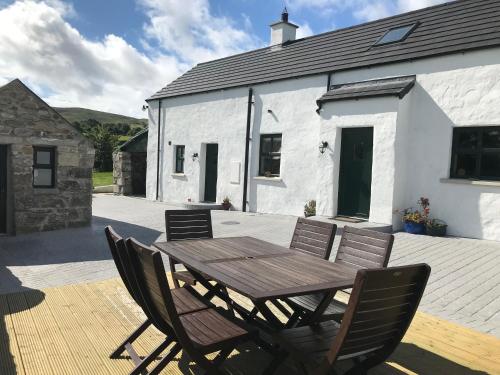 a wooden table and chairs in front of a white building at Mournes Family Cottage with Hot Tub in Hilltown