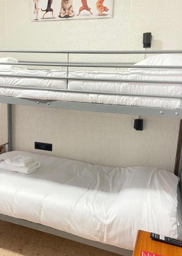 three bunk beds in a room with white sheets at Hotel Arganda in Arganda del Rey