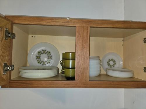 a wooden cabinet with plates and bowls in it at The Happy Place in Glouster