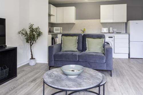 a living room with a blue couch and a table at Charlotte Apartment in Glasgow