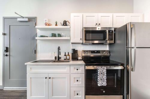 Una cocina con gabinetes blancos y un refrigerador de acero inoxidable. en Steps from Atrium Cozy Macon Getaway, en Macon