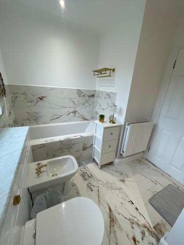 a white bathroom with a toilet and a sink at Beautiful 6 Bedroom House Oxford City in Oxford