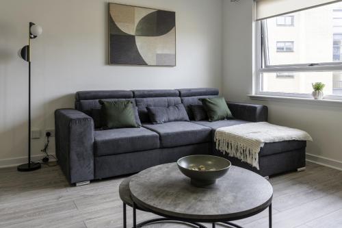 ein Wohnzimmer mit Sofa und Tisch in der Unterkunft Charlotte Apartment in Glasgow