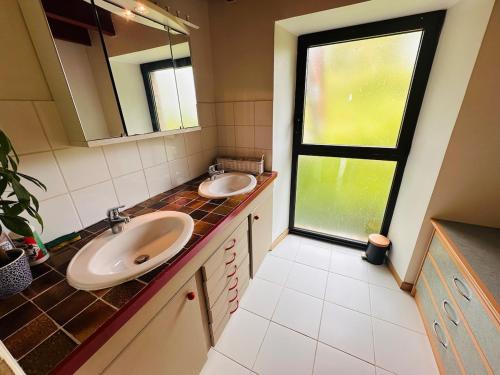 une salle de bain avec deux lavabos et une fenêtre dans l'établissement Maison au calme pour 9 personnes, à La Chapelle-de-Brain