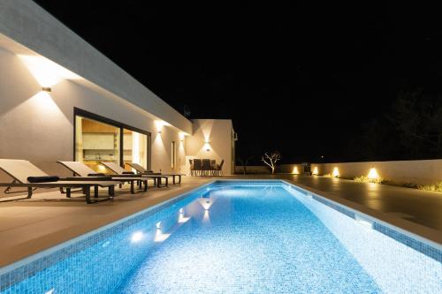 Una piscina en un patio trasero por la noche. en Villa Haba - House with Pool for Families & Couples, en Šišan