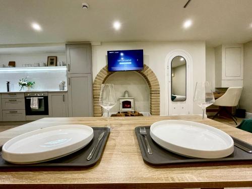 a dining table with two white plates and wine glasses at A2 HighTown Apartment, Steps from Luton Train Station in Luton
