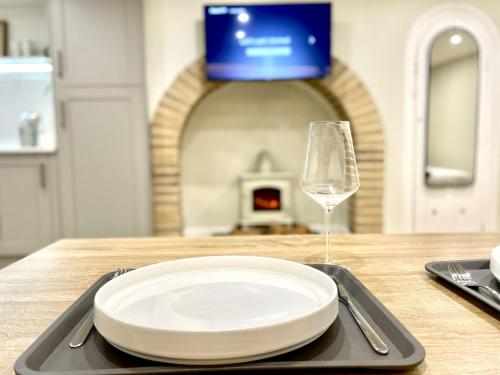 a plate and a glass of wine on a table at A2 HighTown Apartment, Steps from Luton Train Station in Luton