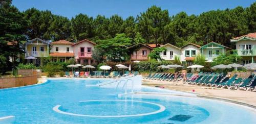 une piscine dans un complexe hôtelier avec chaises et parasols dans l'établissement T2 32m2 terrasse 8m2 PISCINE LACANAU OCEAN LAC GOLF MULTISPORT, à Lacanau