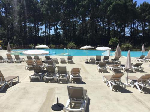 a bunch of chairs and umbrellas and a pool at T2 32m2 terrasse 8m2 PISCINE LACANAU OCEAN LAC GOLF MULTISPORT in Lacanau