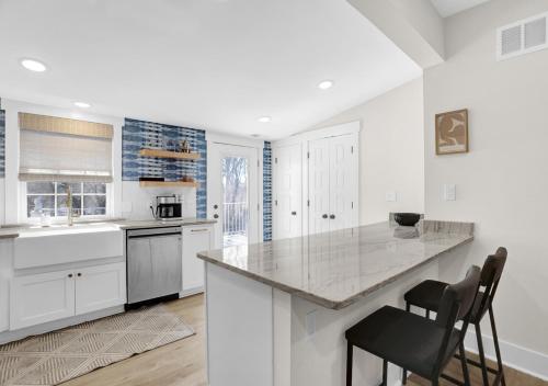 a kitchen with white cabinets and a counter with two chairs at Walk to Memphis Nightlife, 100 Yr Old Cozy Apt in Memphis