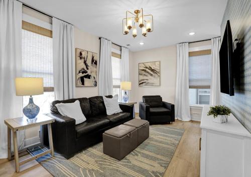 a living room with a black leather couch and a chair at Walk to Memphis Nightlife, 100 Yr Old Cozy Apt in Memphis