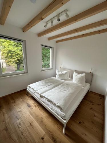 a white bedroom with a bed and two windows at Ferienhaus Domblick Merseburg in Merseburg